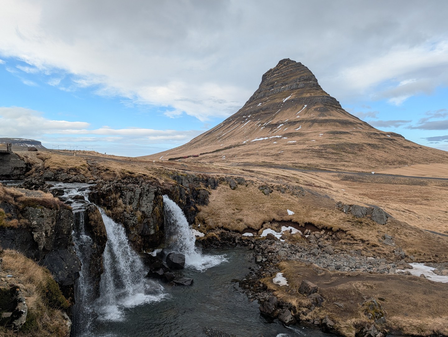 Waterfall and a distinctive pointed mountain beneath a blue sky